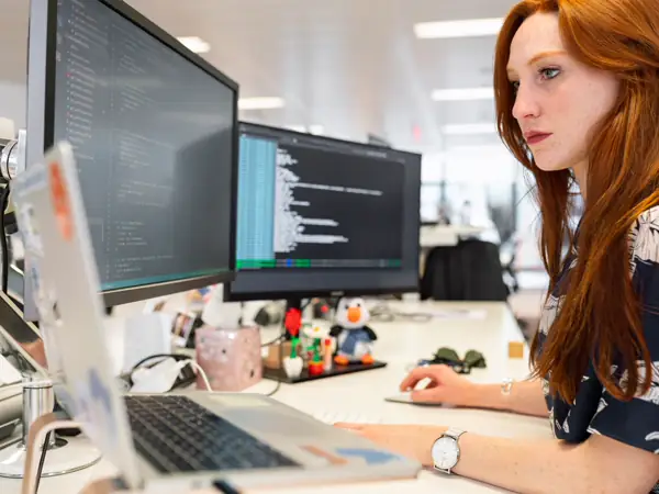 A person working at two monitors at a desk