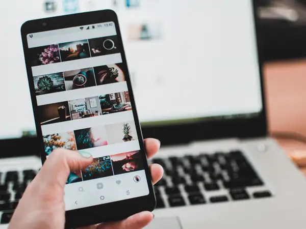 A phone held up showing a wall of photo thumbnails