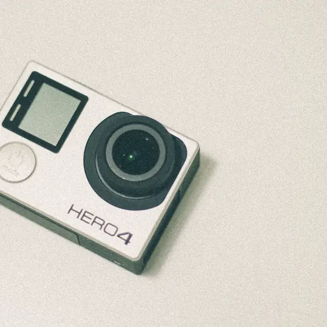 A GoPro HERO4 action camera lying face up on a plain background