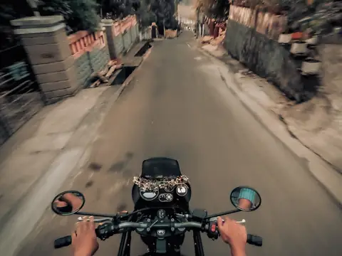 Looking forward over a bike’s handlebars and mirrors on a ride down a street